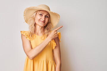 Beautiful mature woman 50 years old pointing finger aside, demonstrating empty space for product or...
