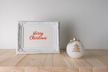 Holiday concept with Christmas bauble and photoframe on wooden table. Creative Christmas or New Year background.
