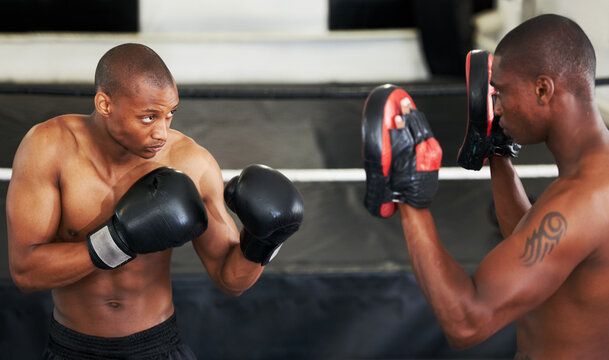 Boxing, coaching and black man with personal trainer for fitness, power or training challenge. Strong body, sparring partner and boxer in gym with fist up, workout and confidence in competition fight - Powered by Adobe
