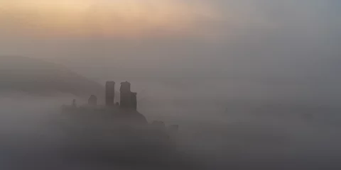 Papier Peint photo Matin avec brouillard Castle perched on a hilltop surrounded by mist at sunrise