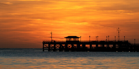 Fiery orange glow of sunrise behind the close up of a silhouetted prier