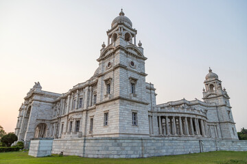 Fototapeta premium View of The famous Victoria Memorial with Garden, a large marble building in Central Kolkata, at the time of Sunrise.
