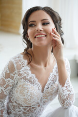 Portrait of a smiling beautiful girl bride in a long lace dress with an elegant hairstyle.