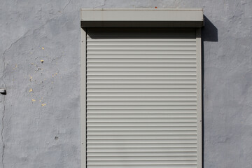 Closed metal blinds on a gray wall.