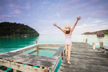 Young Asian lady tourist on the wooden bridge in to the sea on her holiday. Koh Kood island, Trat province, Thailand