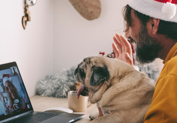 One woman doing video call on laptop with his old dog pug best friends and happy woman on the other side of computer connection display. Remote friends during christmas holiday celebration time - obrazy, fototapety, plakaty
