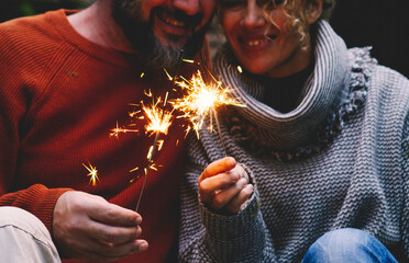 Man and woman in relationship celebrate together anniversary with sparkler lights in outdoors...