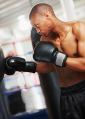 Boxing, gloves and black man training in gym with fitness, power and workout challenge. Strong body, muscle and boxer in club, athlete fighting with bag for exercise and confidence in competition.