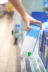 Hand taking a milk carton from supermarket shelf ready for consumption