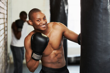 Boxing, gloves and portrait of black man with bag, smile and fitness, power and training challenge. Strong body, muscle and happy boxer in gym, athlete with confidence and pride in competition fight