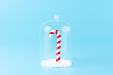 Christmas candy under the glass dome on blue background. Minimal New Year wallpaper. Holiday...
