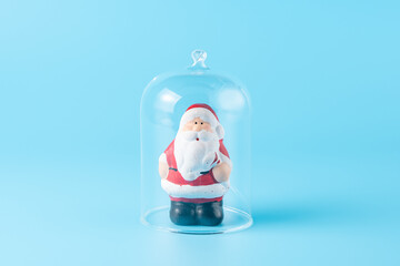 Santa Claus under the glass dome on blue background. Minimal New Year wallpaper. Holiday...