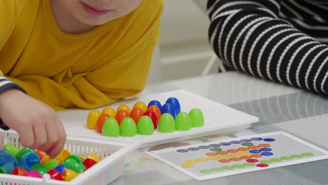 mother and child playing together pegboard mosaic. Early child development. Fine motor skills. Learning and creativity