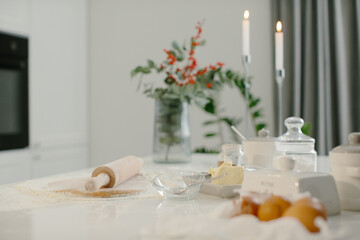 Kitchen table with ingredients for baking cookies and Christmas decorations.