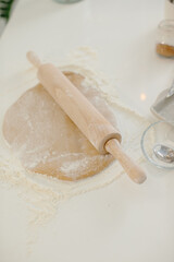Close up of cookie dough and rolling pin on kitchen table.