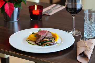 Close up Gourmet tasty roast beef steak with mashed potatoes and other vegetables on a white plate, served food in a restaurant, wine
