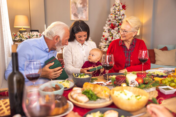 Grandparents giving Christmas presents to their granddaughter