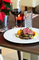 Close up Gourmet tasty roast beef steak with mashed potatoes and other vegetables on a white plate, served food in a restaurant, wine