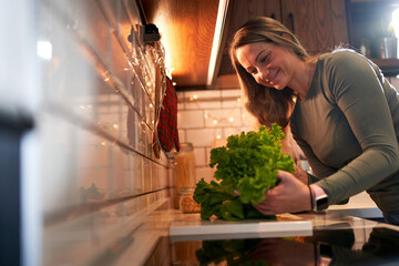  A cheerful woman in the kitchen, checking the salad with a smile, preparing for a delightful...