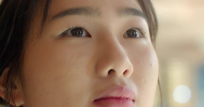 An Asian female student in a white school uniform is looking blankly upwards.