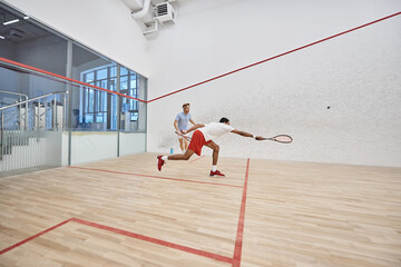 dynamic multicultural sportsmen playing squash together inside of court, challenge and motivation