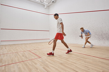 active and diverse men in sportswear playing squash inside of court, challenge and motivation