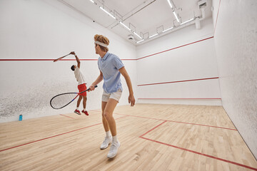 interracial men in sportswear playing squash together inside of court, fitness and motivation