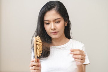 Serious asian young woman holding brush holding comb, hairbrush with fall black hair from scalp after brushing, looking on hand worry about balding. Health care, beauty treatment, hair loss problem. - obrazy, fototapety, plakaty