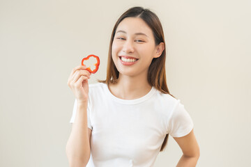Healthy diet food with capsicum, portrait smile of asian young woman holding, eating red bell pepper isolated on background, fresh vegetable from nature organic for wellness, happy nutrition lifestyle