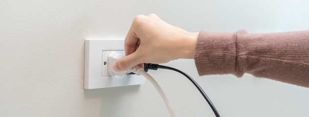 Hand of woman plugged in, unplugged electricity cord cable at home, put on or remove electric plug...