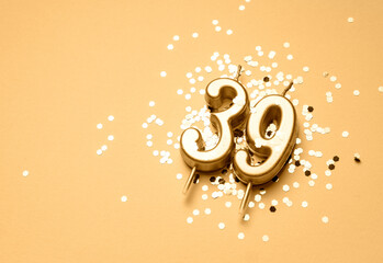 39 years birthday celebration festive background made with golden candle in the form of number Thirty nine lying on sparkles. Universal holiday banner with copy space.