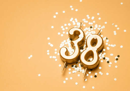 38 years birthday celebration festive background made with golden candle in the form of number Thirty eight lying on sparkles. Universal holiday banner with copy space.