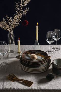 winter holidays, dinner party and celebration concept - crockery and candles for scandinavian christmas table serving over black background