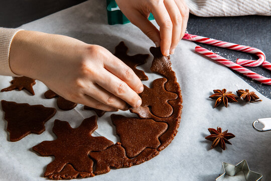 baking, cooking and christmas concept - close up of hands making cookies of gingerbread dough on black kitchen table top