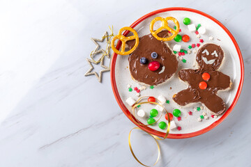 Fototapeta na wymiar Funny Christmas symbols toasts with chocolate paste, xmas candies and fruits. Christmas morning snack, breakfast, idea for children's holiday party food