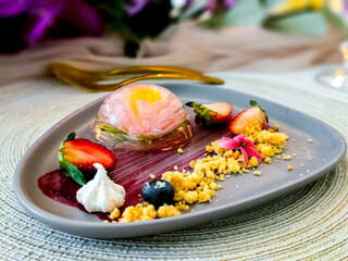 Pink of flowers in jelly on a blue plate serve with blueberry, strawberry and crumble. Deliciuos pudding and jelly cake. ...