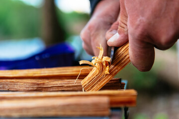 Closeup of a hand whittling fire starter wood with a sharp knife at a campsite