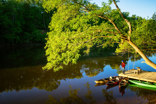 A man in a red jacket stands on a boat dock in the sun along the cape fear river in north carolina