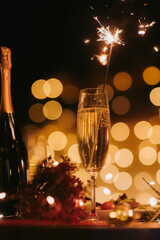 Night shot of flute with Champagne and sparkler with warm bokeh and atmosphere of New Year Eve