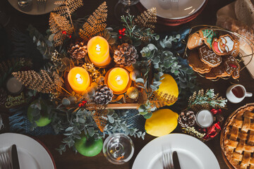 Top view of beautiful decorated Christmas table with candles cookies wine glasses plates. Christmas...
