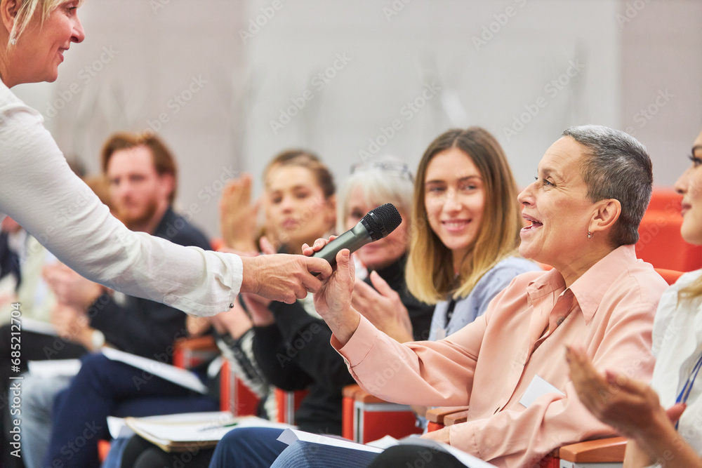 Wall mural speaker giving microphone to audience at business event