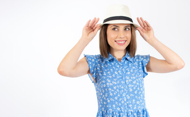 Obraz na płótnie Canvas Beautiful young woman laughing woman in blue dress and straw hat looking happy over white background