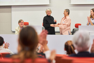 Orators handshaking on stage at business event in auditorium - obrazy, fototapety, plakaty