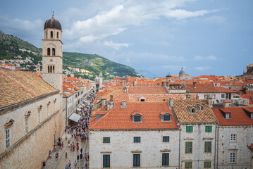 View to the red roofs of Dubrovnik Old town on summer day. Crowd of people walking in the streets