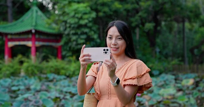 Woman use mobile phone to take photo in water pond