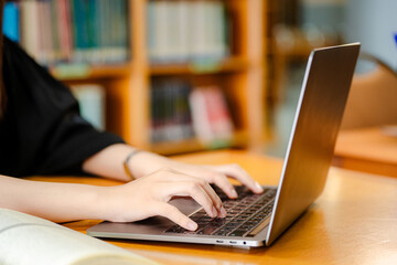 Female student using laptop on desk at library