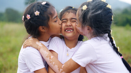 Three little cute child asia sisters kiss cheek cuddle hug look at camera smile fun having good...