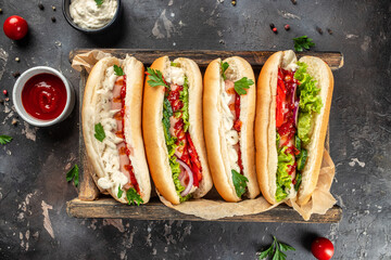 Various hot dog with vegetables, tomato, lettuce, sausage in a bun with sauces on a dark...