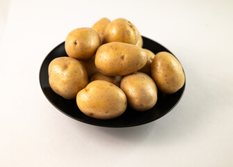 Potatoes are piled on a black plate on a white background