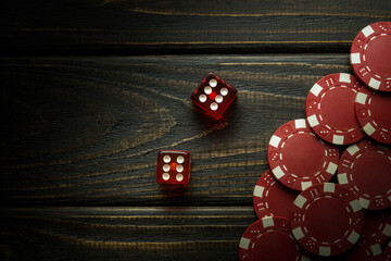 Two poker dice with a winning combination of twelve and chips from a successful bet. Free space for advertising on a dark background - obrazy, fototapety, plakaty